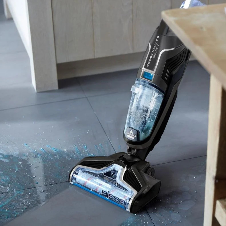 Een stofzuiger die een vloer schoonmaakt, met water dat wordt gespoten. Toont de reiniger en de vloer.