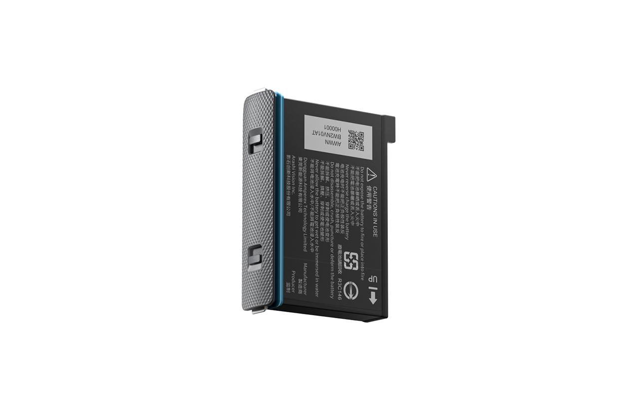 Schwarze und silberne Batterie, beschriftet mit Text und einem QR-Code, vor weißem Hintergrund. Die Seite hat ein Gittermuster.