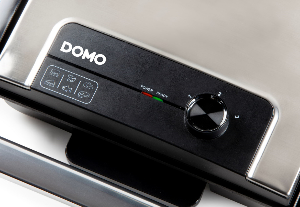 Close-up of a black and silver electric grill control panel, DOMO logo, and dial.