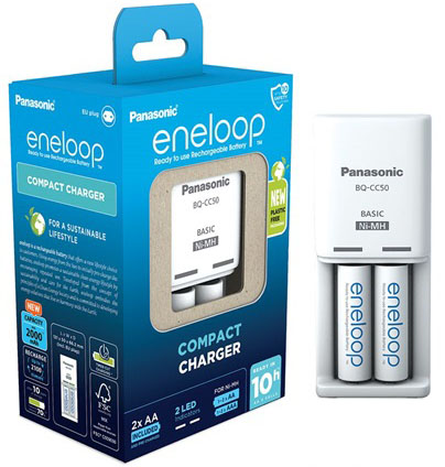 Egy fehér és kék doboz elemekkel és egy 'Panasonic eneloop Compact Charger' feliratú töltővel.