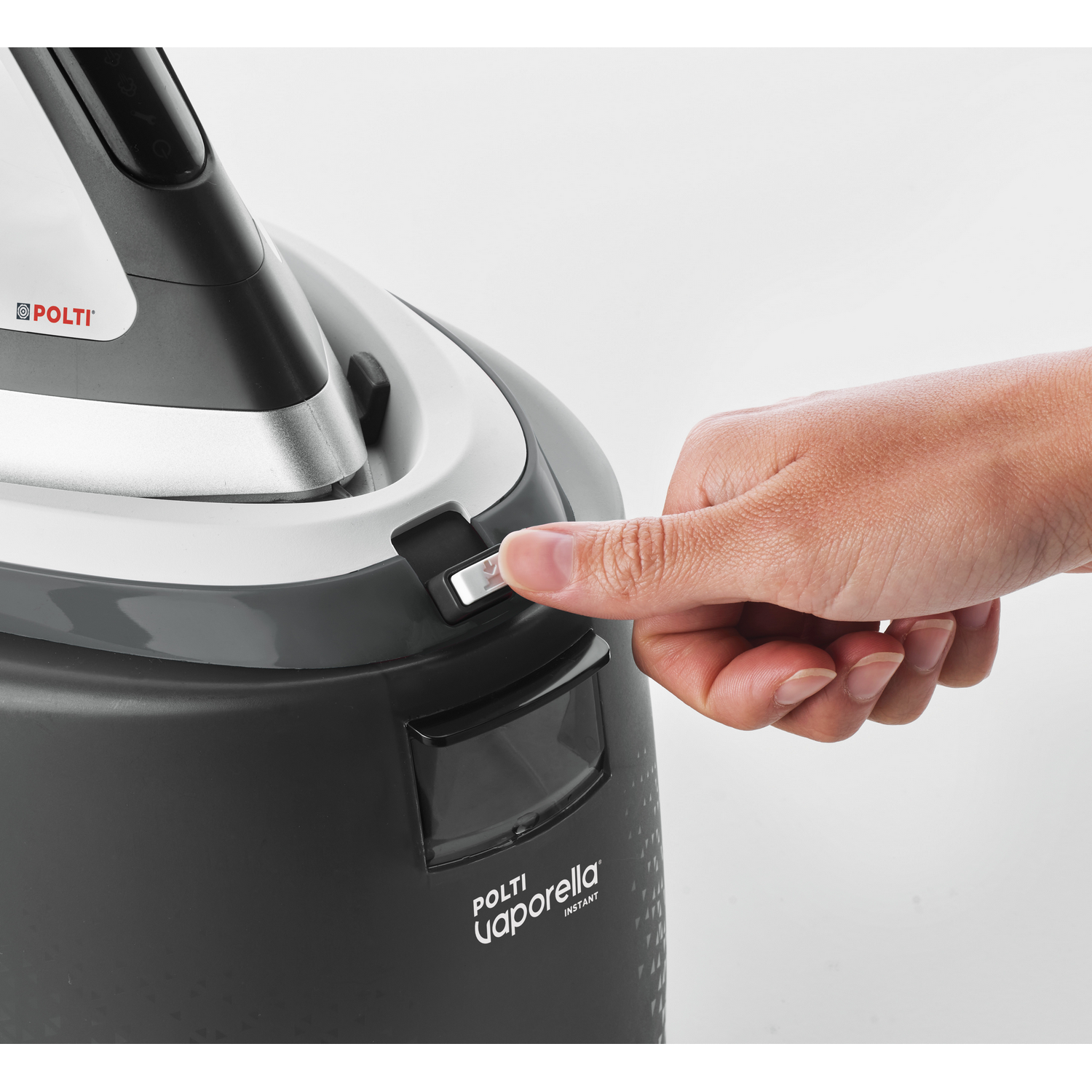 Mano de una persona presionando un botón en un vaporizador de prendas en blanco y negro.