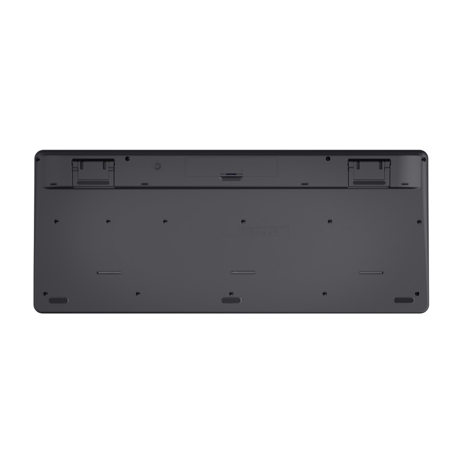 Vista inferiore di una tastiera wireless nera. Ha piedini in gomma e porte di connessione.