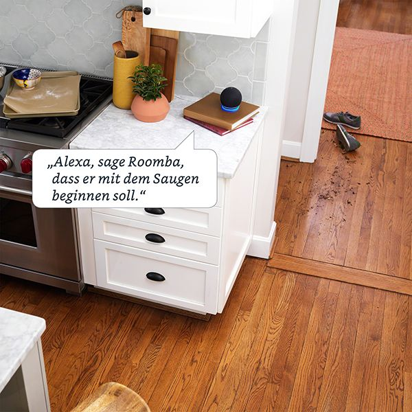 Scène de cuisine avec haut-parleur intelligent sur le comptoir. Texte : Alexa, dis à Roomba de commencer à aspirer.