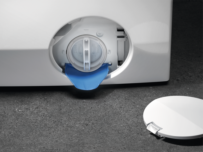 Accès au filtre de vidange de la machine à laver avec languette bleue et couvercle blanc.