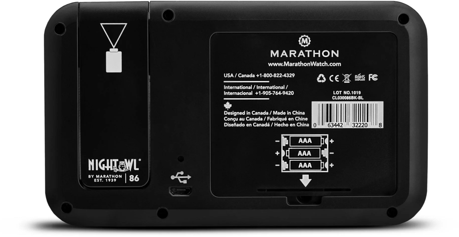 Back of a black digital clock showing the battery compartment, branding, and USB port.
