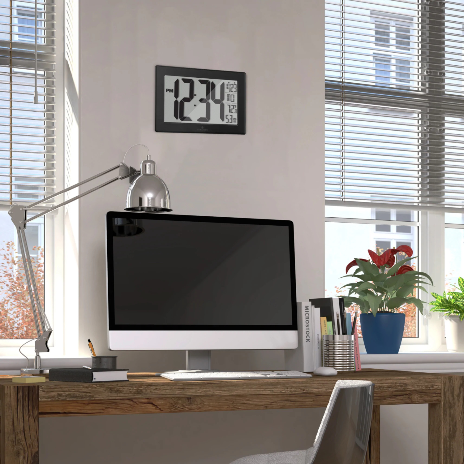 Bureau avec ordinateur, horloge, lampe et plantes près d'une fenêtre à stores.
