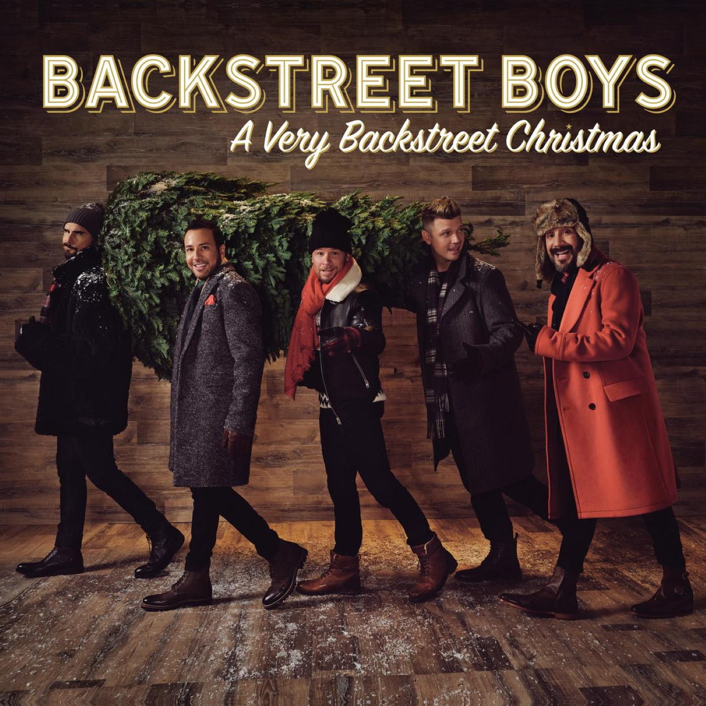 Backstreet Boys egy karácsonyfát cipelnek, album borító. Öt férfi téli öltözetben.