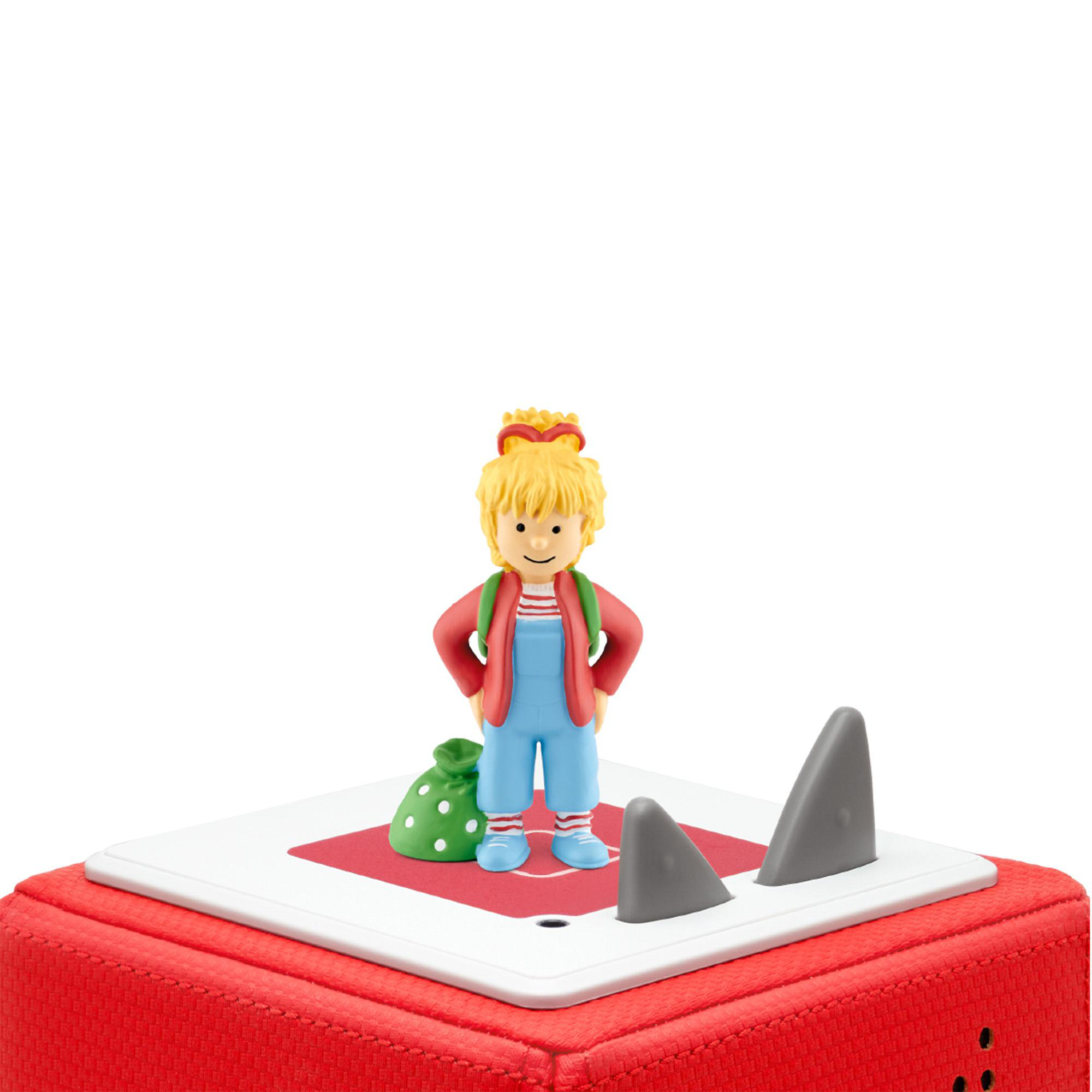 Spielzeugfigur eines Kindes mit Tasche und Haifischflossen auf einem roten Würfel.