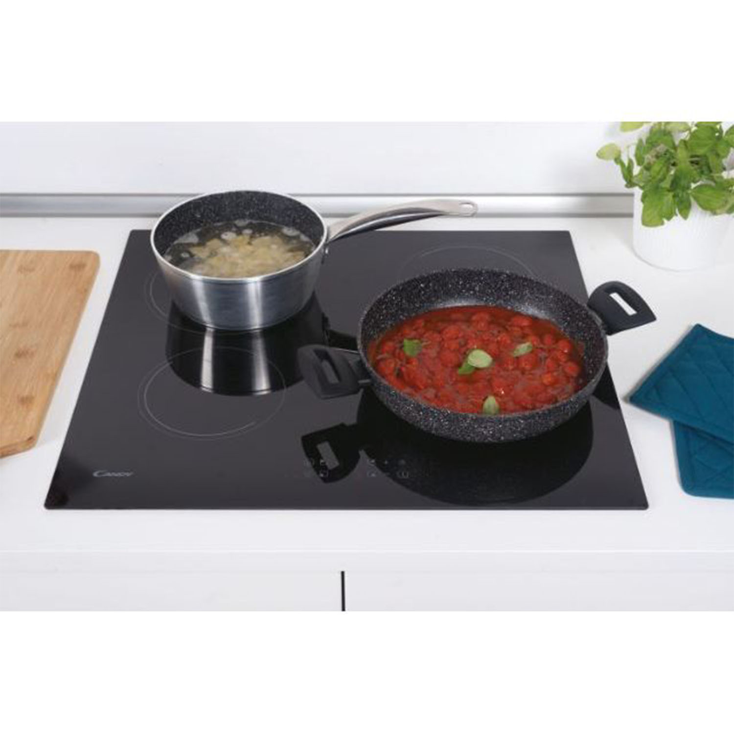 Piano cottura a induzione nero con due pentole. Una con pasta, una con salsa di pomodoro.