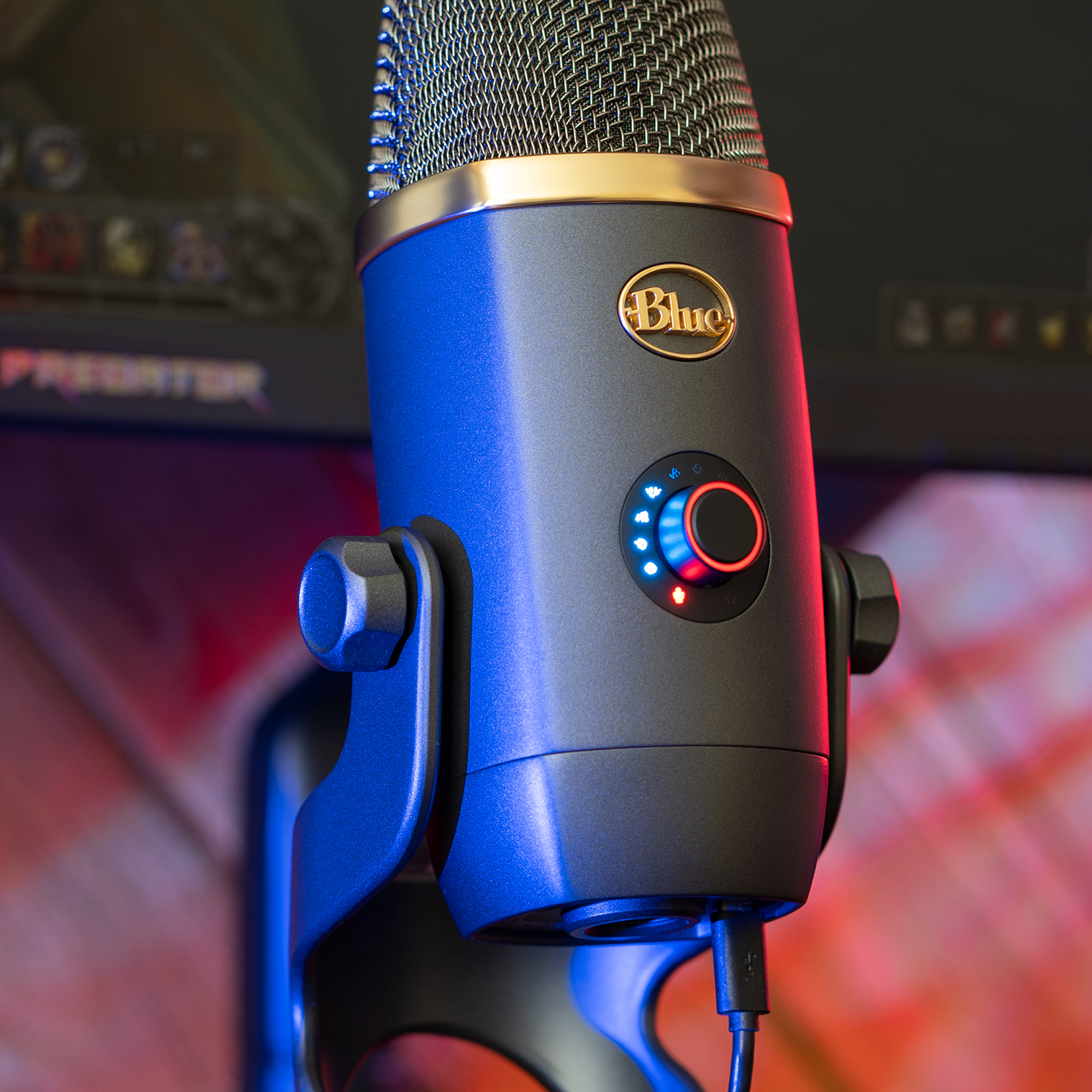 Un micrófono Blue Yeti azul y negro, con un anillo dorado y una pantalla en el fondo.