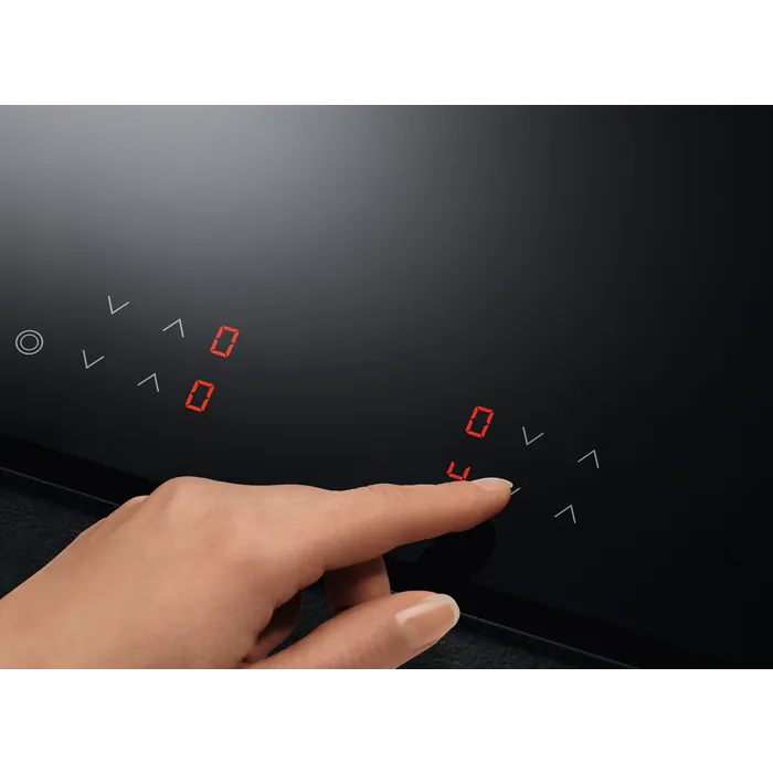 Mano tocando una placa de inducción negra, con números rojos.