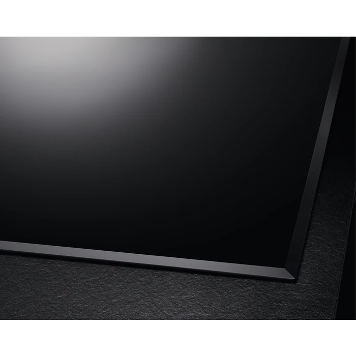 Una placa de inducción negra. La superficie es plana y brillante, con fondo de piedra oscura.
