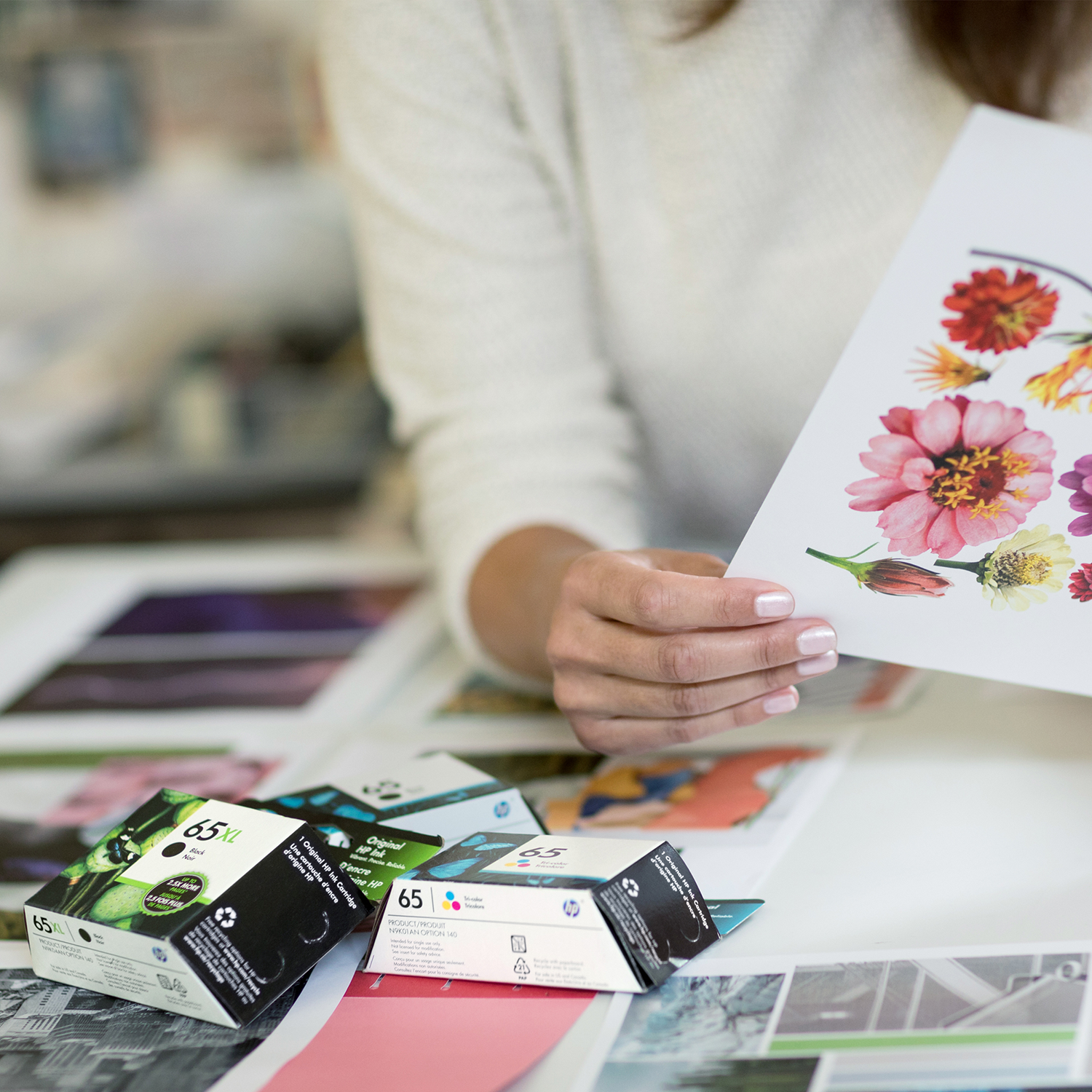 Femme tenant une impression de fleurs, à côté des cartouches d'encre.