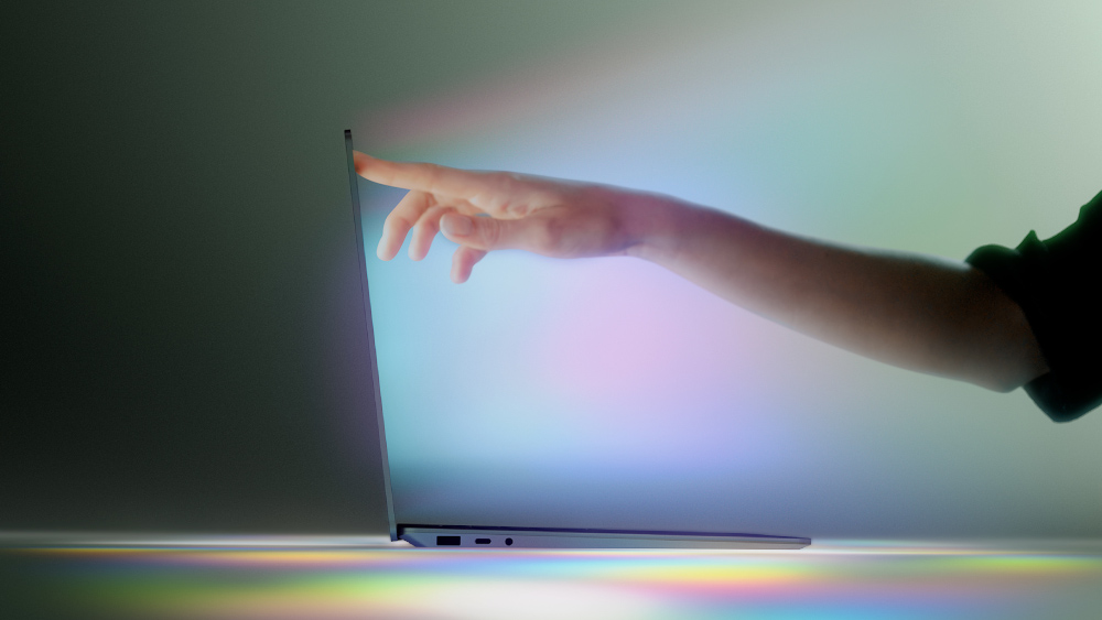 Main touchant un écran d'ordinateur portable avec de la lumière qui en émane.