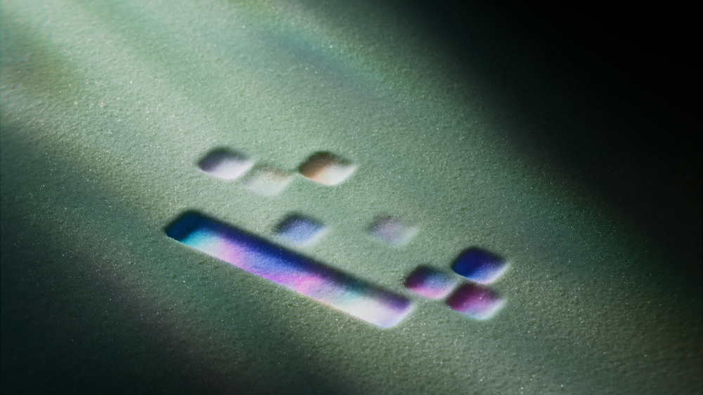 Image abstraite avec un fond vert texturé. Formes géométriques avec des dégradés arc-en-ciel sont visibles.