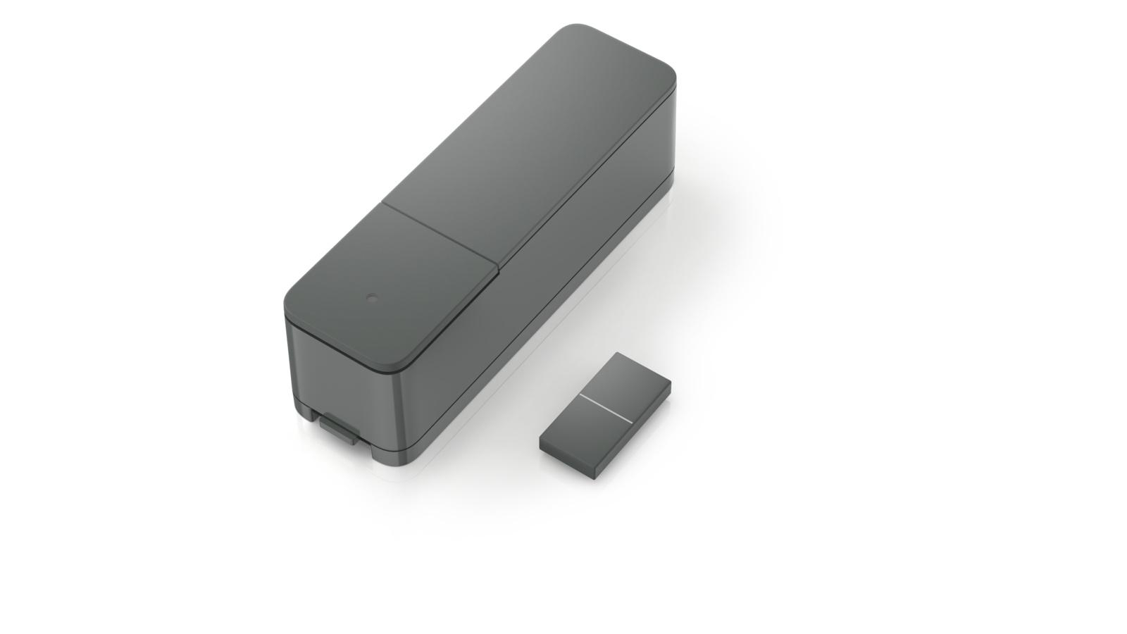 Dunkelgraues Gerät mit kleiner Fernbedienung. Beide auf weißem Hintergrund, Draufsicht.