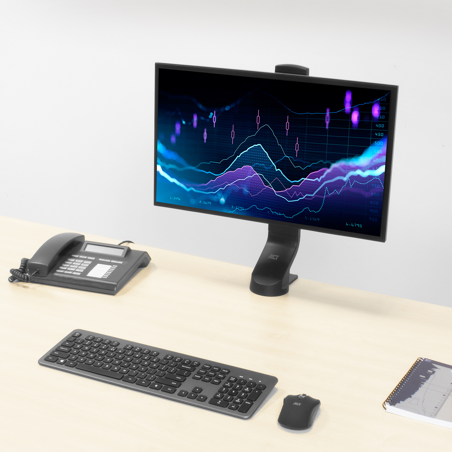 A computer monitor displays a graph, with a keyboard, mouse, and phone on a desk.