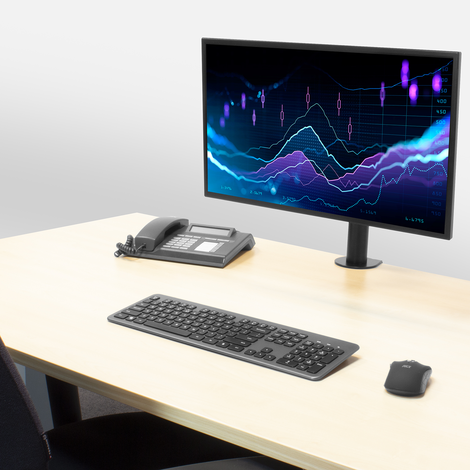 Office desk with a monitor displaying charts, a keyboard, a mouse, and a telephone. Gray and beige colors.