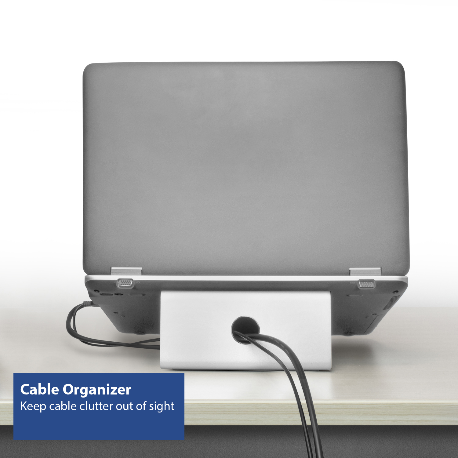 Laptop resting on a white cable organizer. Black cables are coming out of the organizer. White background.