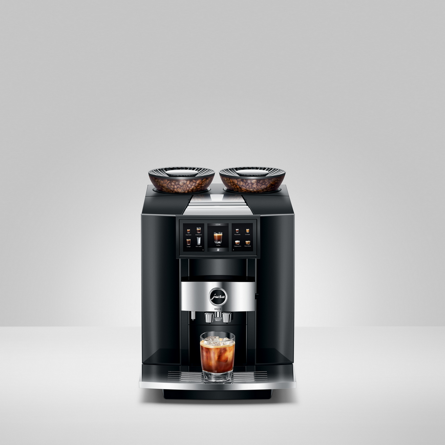 A black Jura coffee machine with two bean containers and a glass of iced coffee.