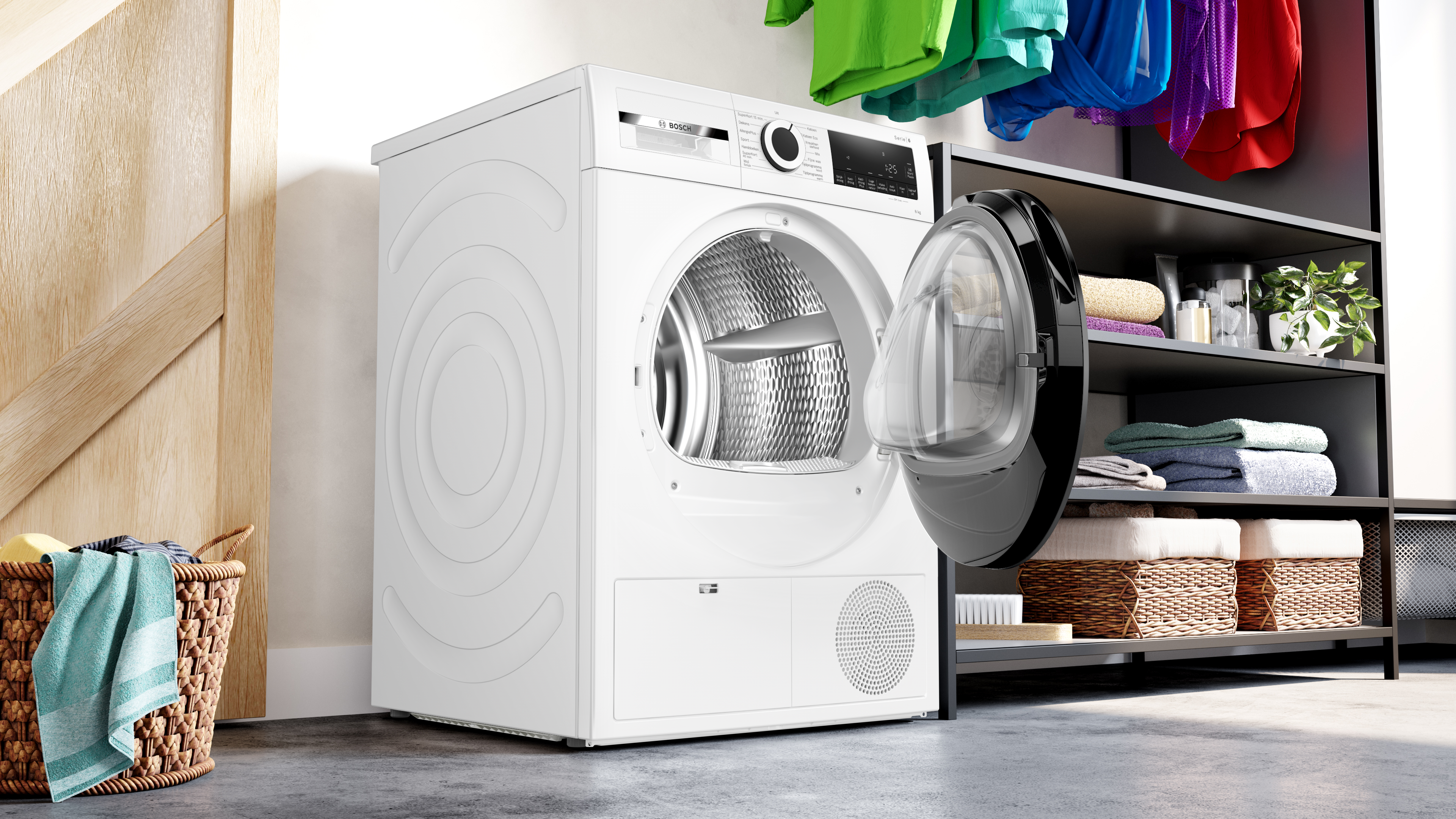 Witte wasmachine met open deur, kleding, manden en een houten deur.