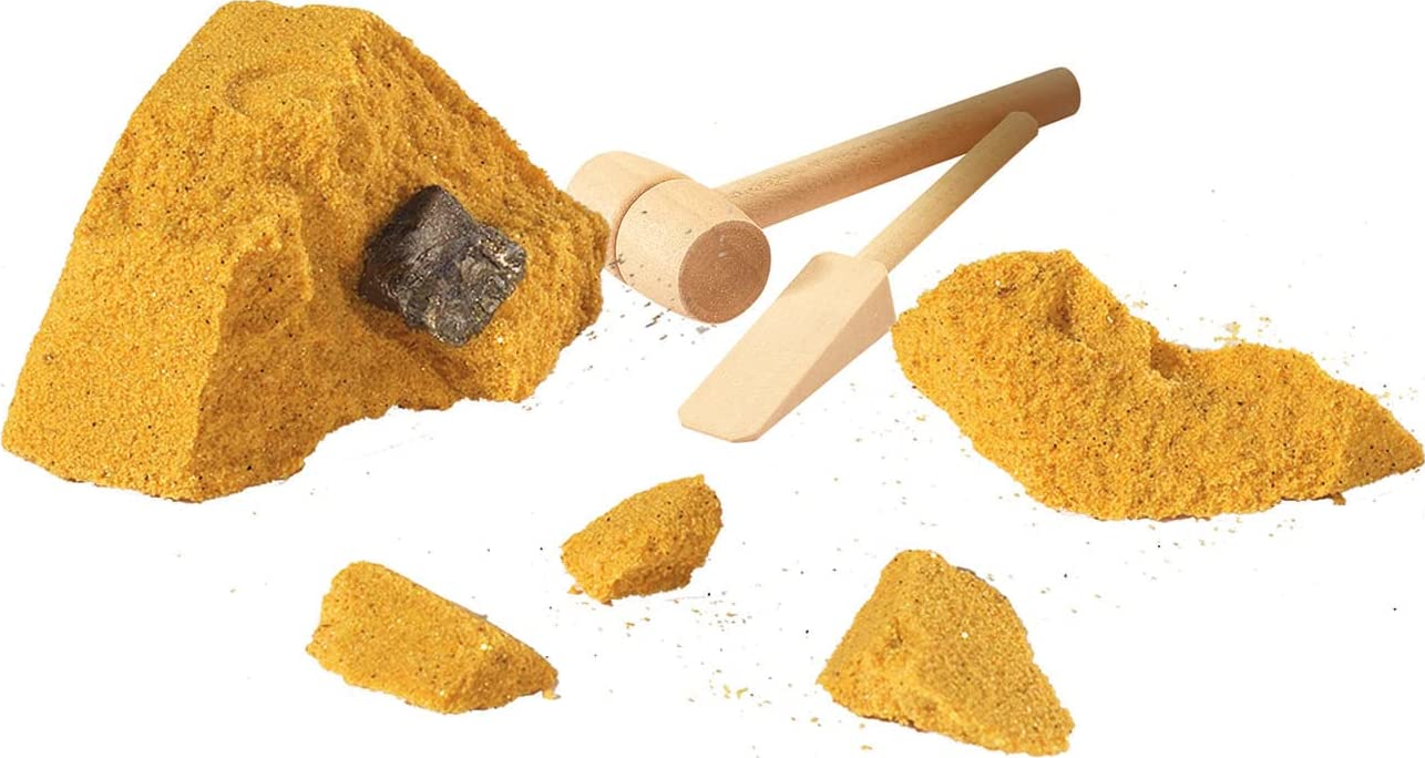 Ein Spielzeug-Mining-Kit mit gelbem Sand, Steinen, einem Hammer und einem Meißel.