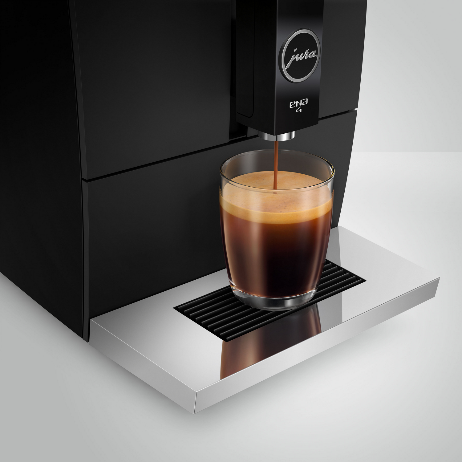 Black Jura ENA 4 coffee machine pouring coffee into a glass. Stainless steel tray, white background.