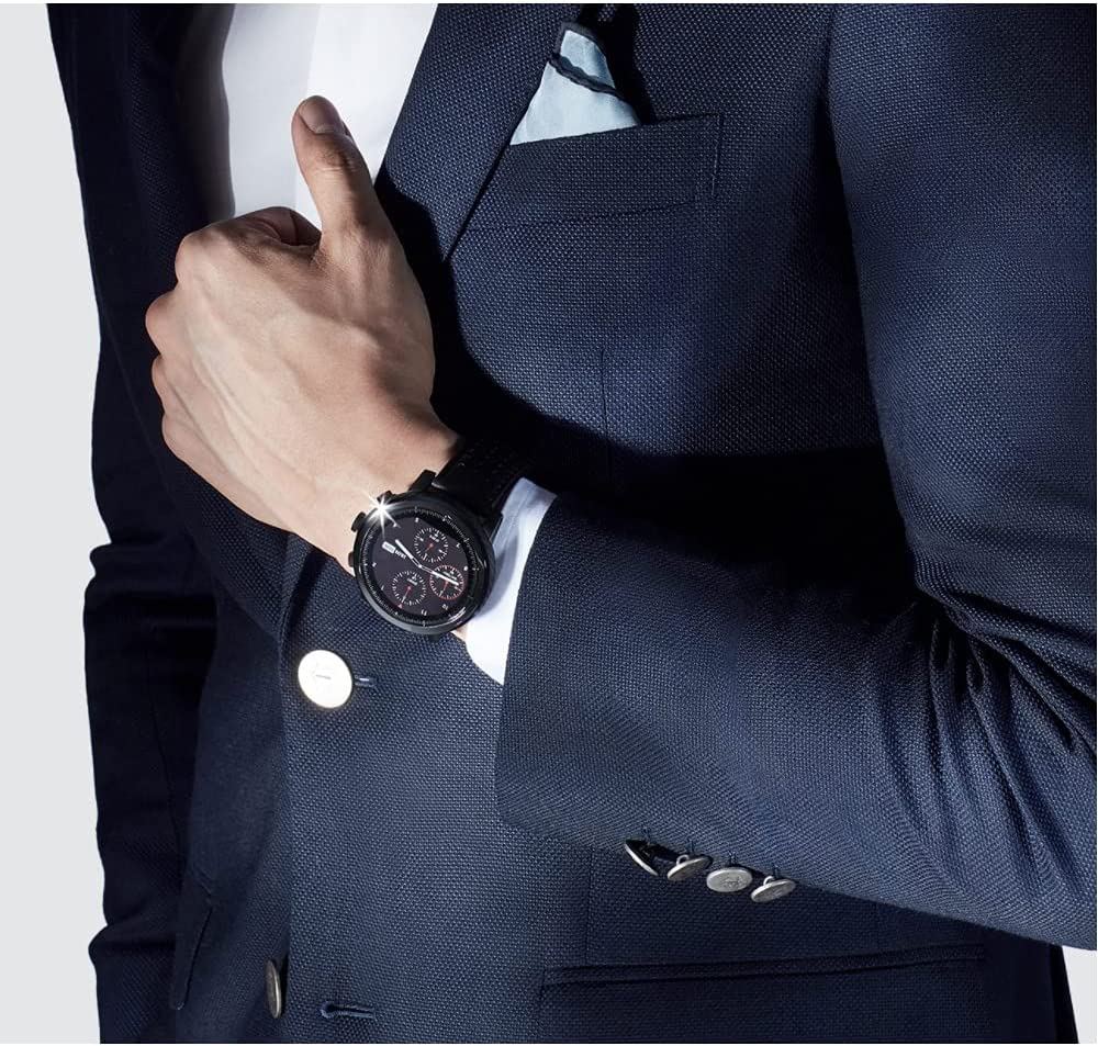 Un hombre con un traje azul marino con un reloj en la muñeca y una camisa blanca con pañuelo de bolsillo.