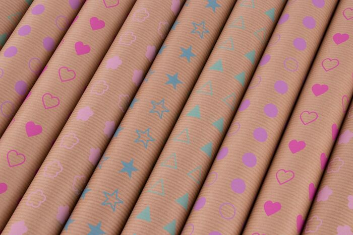 Papel de regalo enrollado con patrones repetidos de corazones, estrellas y nubes.