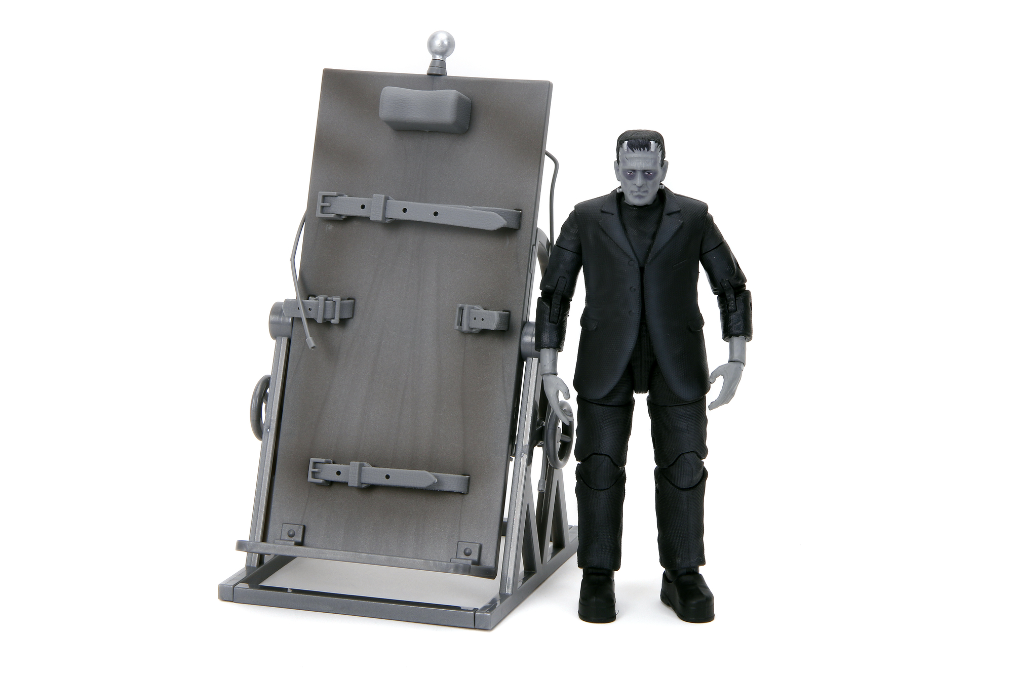 Frankenstein-Spielzeugfigur steht neben einem grauen medizinischen Untersuchungstisch.