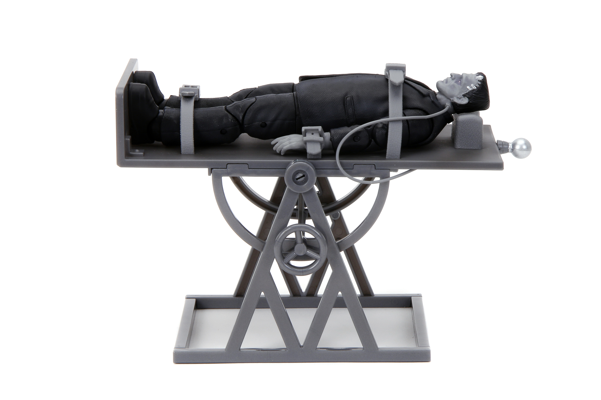Frankenstein-Figur auf einem Tisch liegend. Tisch hat einen Mechanismus unten und Gurte oben.