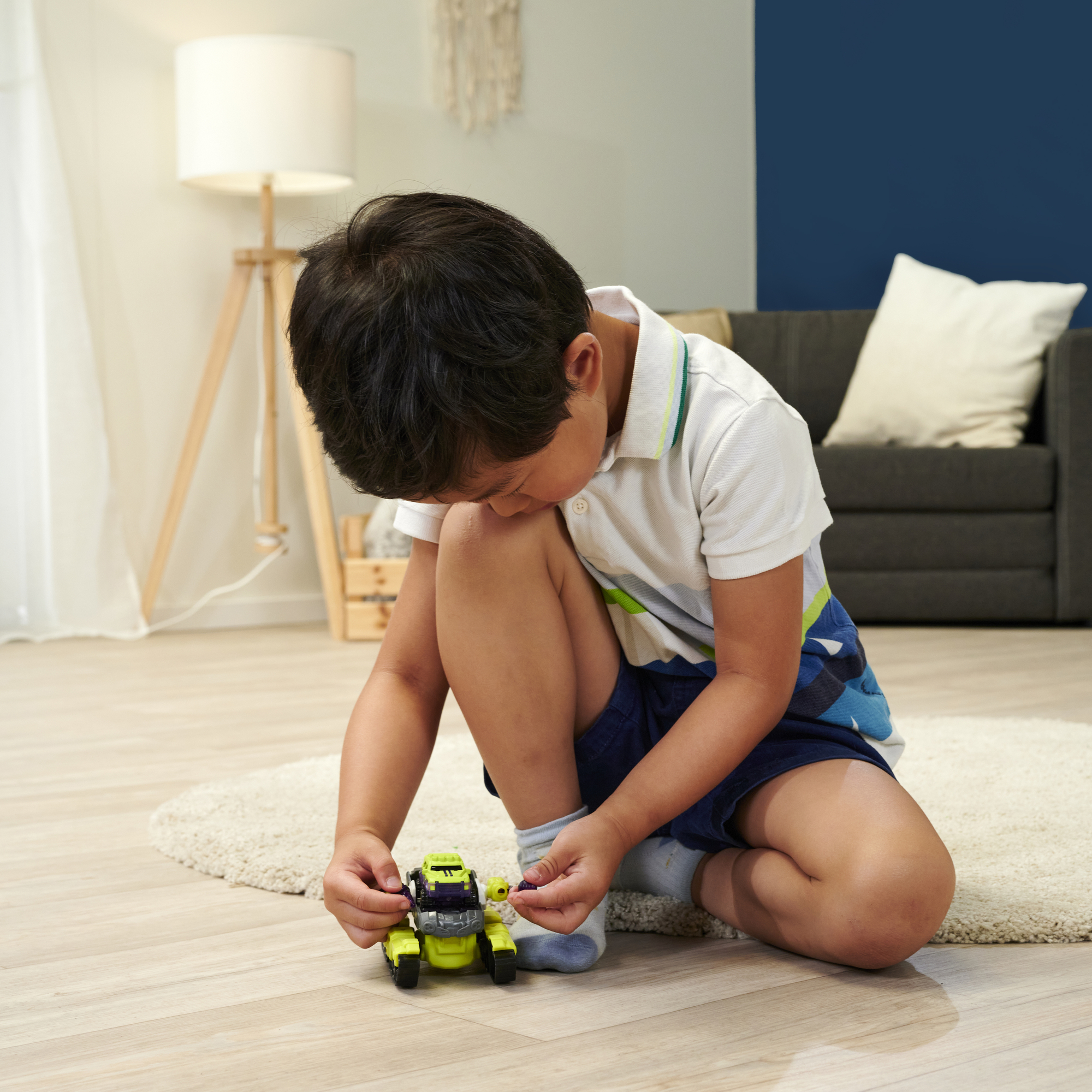 Ein kleiner Junge spielt auf dem Boden mit einem Spielzeugauto.