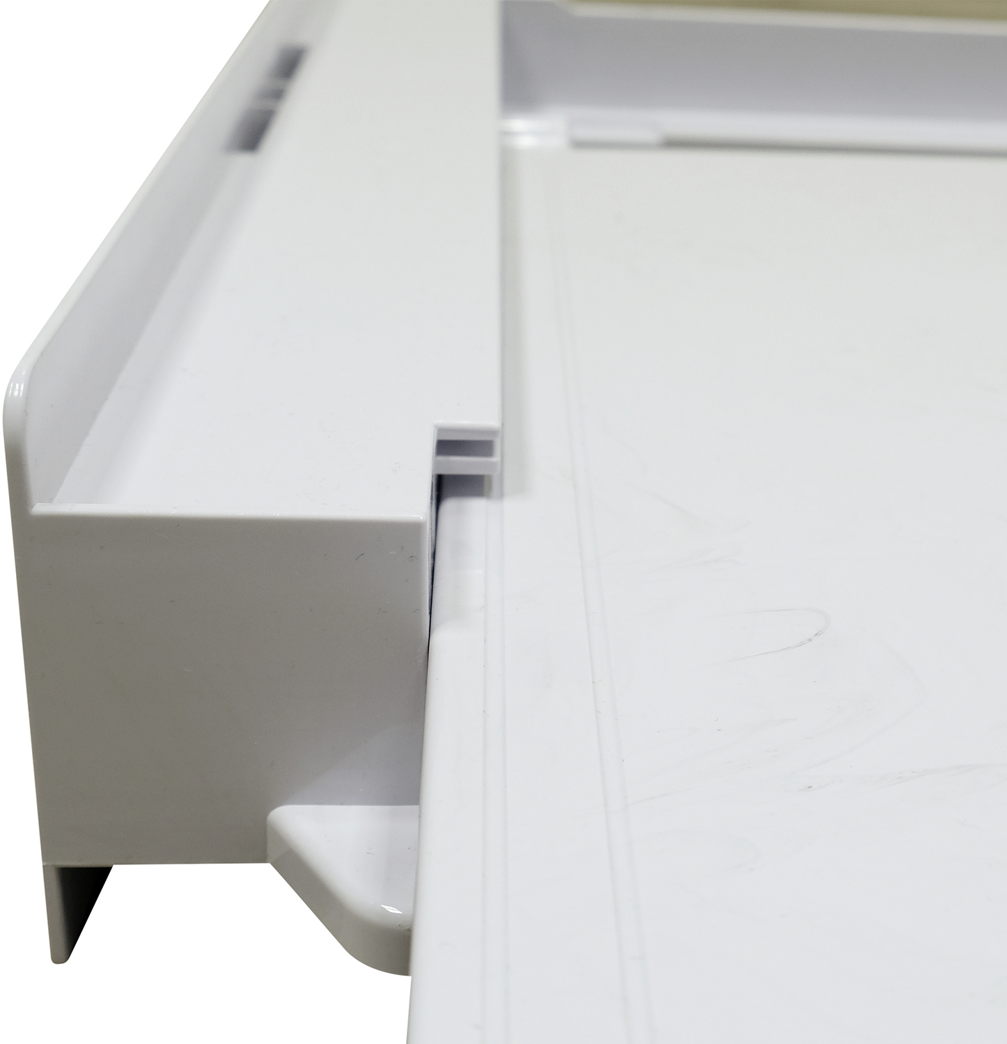 Close-up of a white shelf edge with a small, rectangular recess and a raised edge.