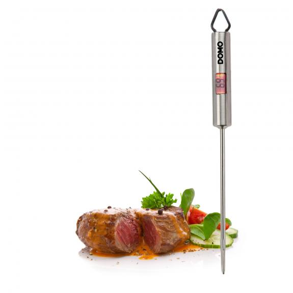 Steak and salad with a thermometer in it on a white surface. 