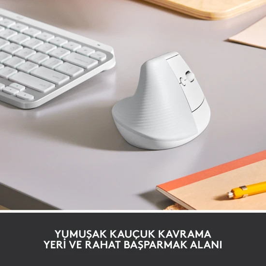 Beyaz ergonomik fare bir masada. Başparmak dayanağı ile tarafı gösterir. Beyaz klavye ve not defteri.