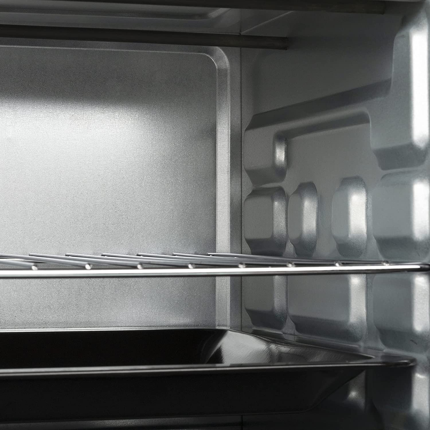Interno di un forno argentato. C'è una griglia e un vassoio nero in basso.