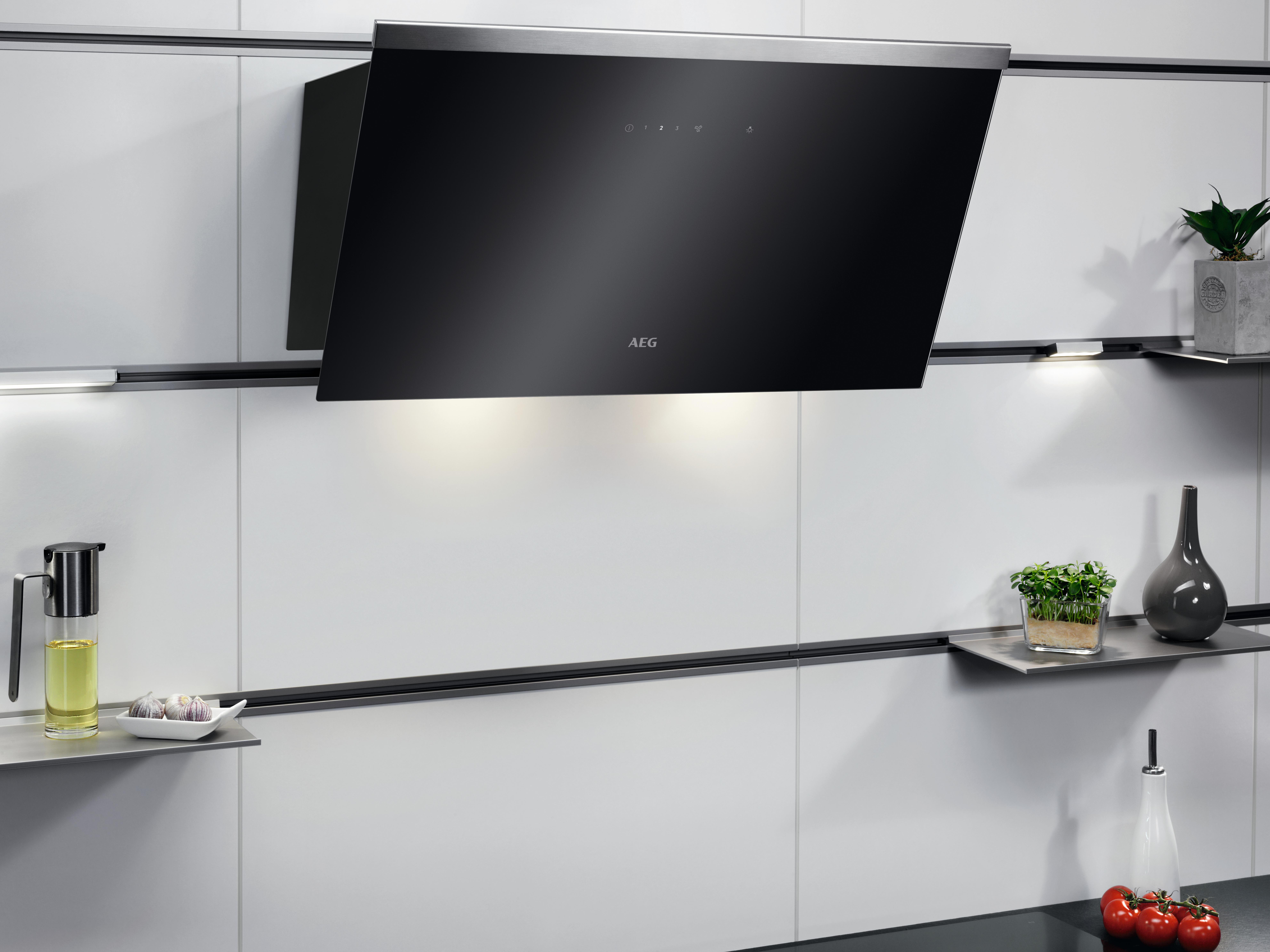 Schwarze Dunstabzugshaube an einer weißen Wand über zwei Regalen. Eine Küchenszene mit Lichtern.