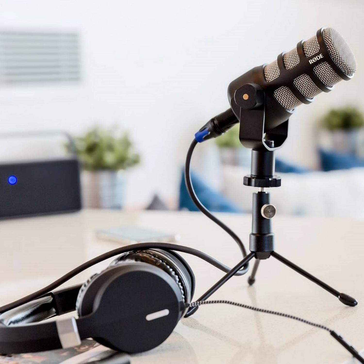 A RØDE microphone on a tripod with headphones and speaker.
