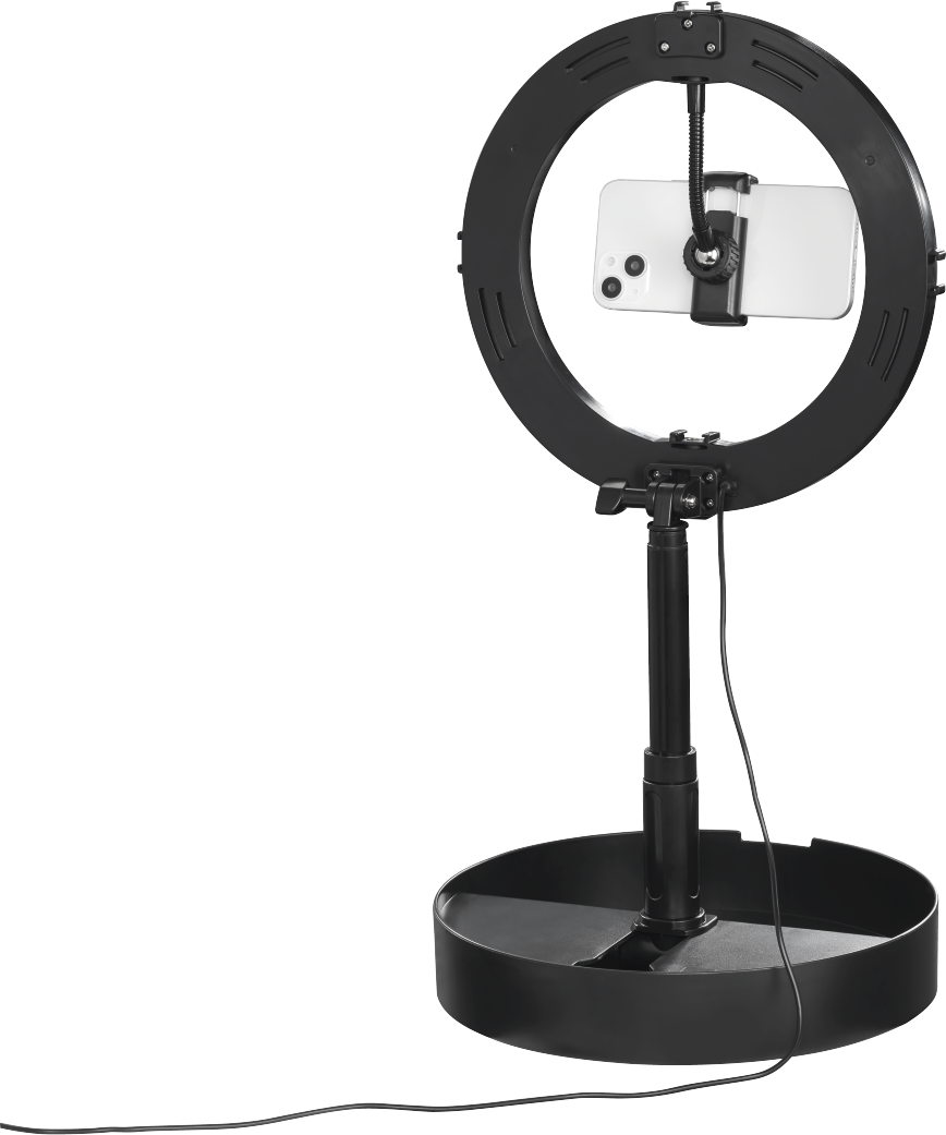 Una luce ad anello nera con un supporto per telefono, su un supporto. Sfondo bianco.