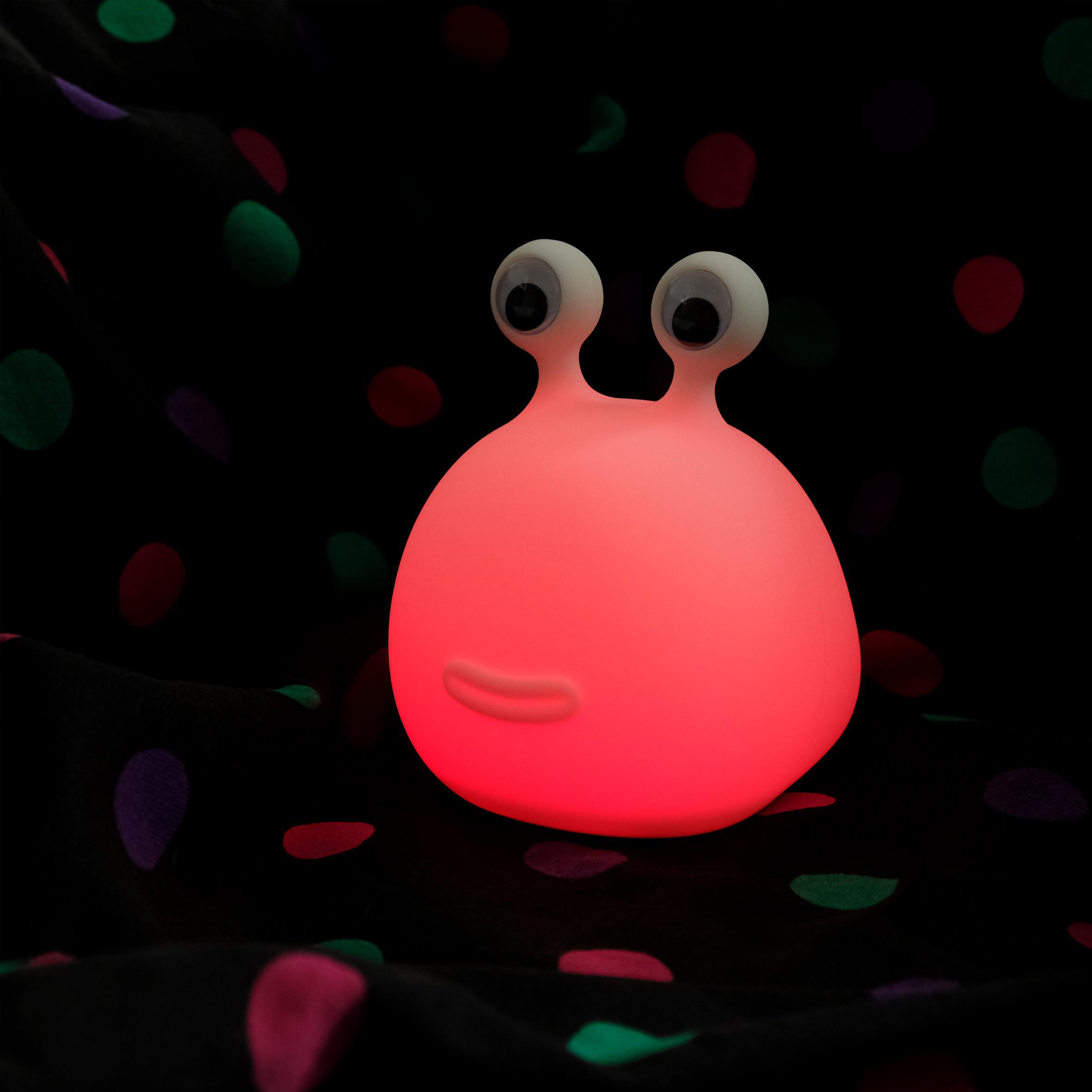 Eine rosa leuchtende Cartoonfigur mit großen Augen und Mund, vor einem gepunkteten Hintergrund.