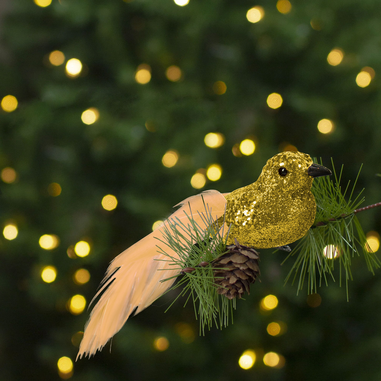 Arany madár dísz fenyőágon, bokeh fényekkel a háttérben.