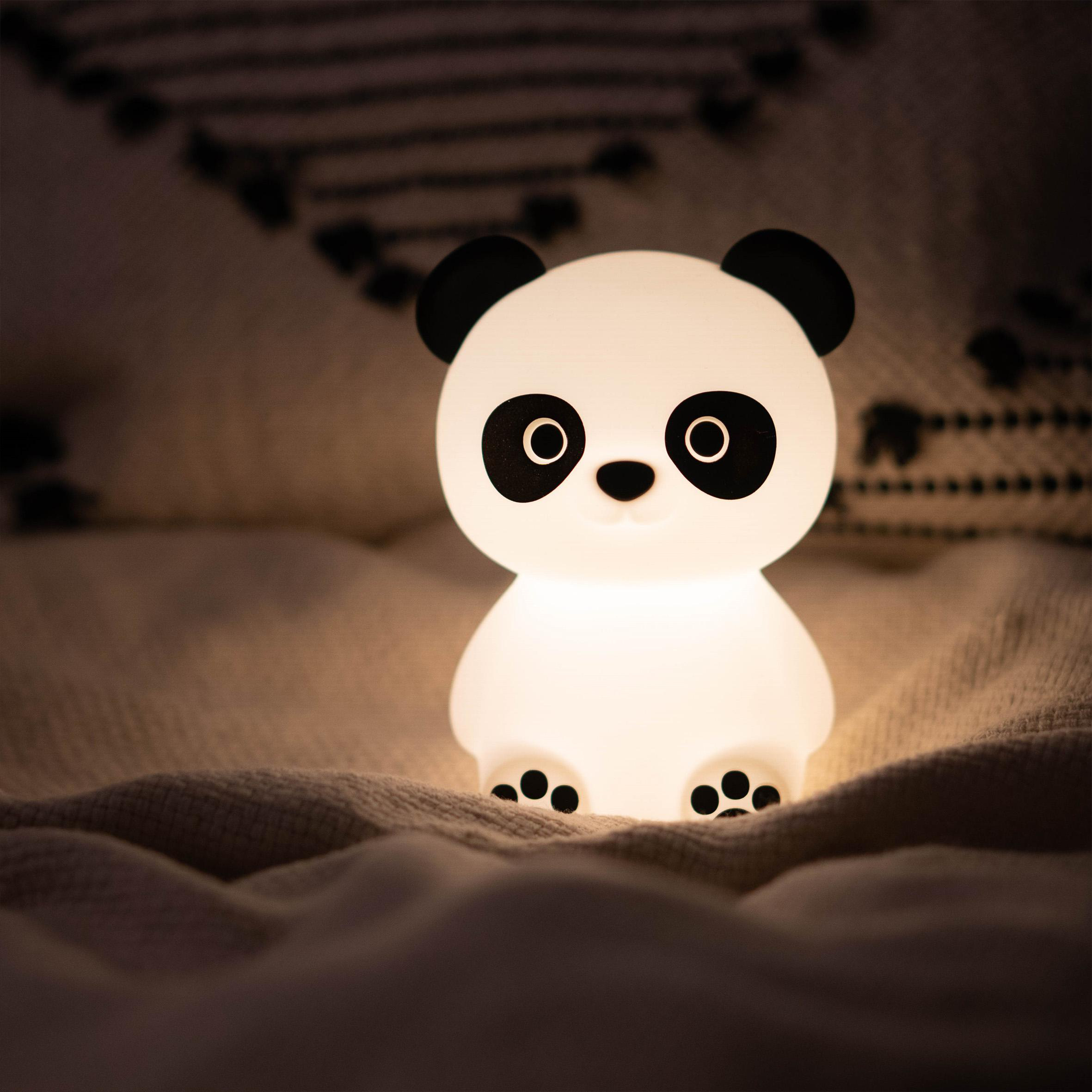 Eine weiße Panda-förmige Lampe, die sanft in einem schwach beleuchteten Raum leuchtet.