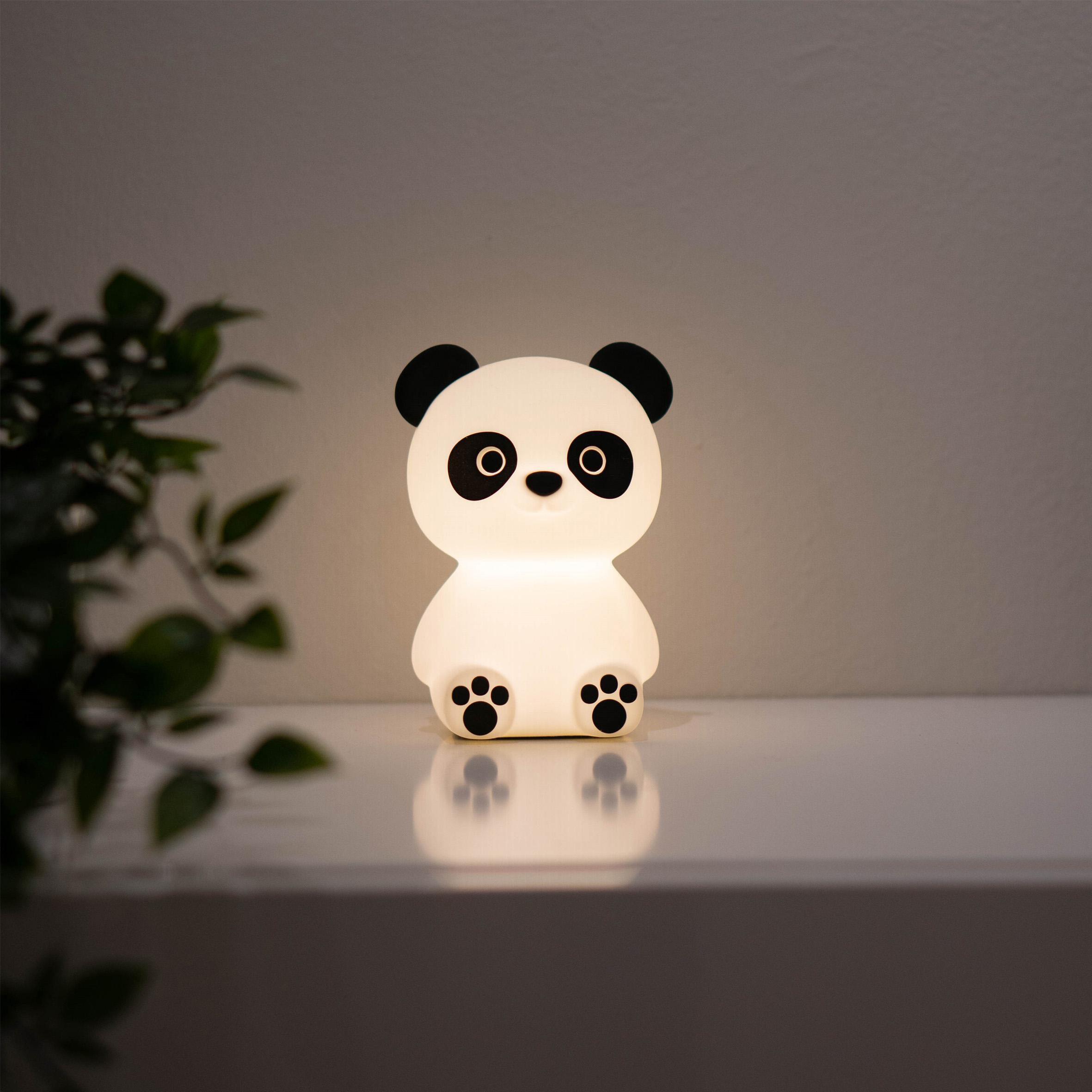Panda-förmige Lampe auf einem Regal, leuchtend. Weißer und grauer Hintergrund.