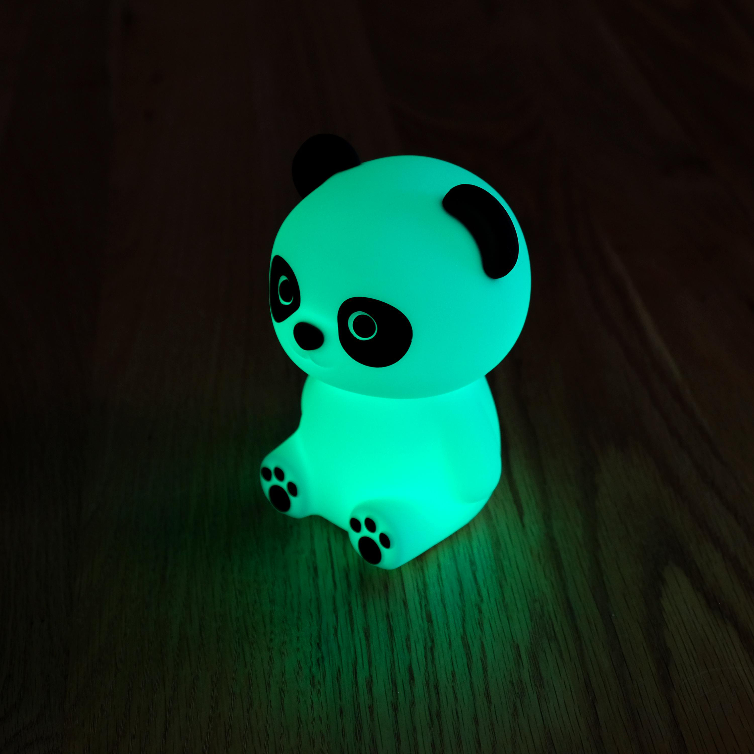 Grün leuchtendes Panda-Nachtlicht auf Holzoberfläche, in dunkler Umgebung.