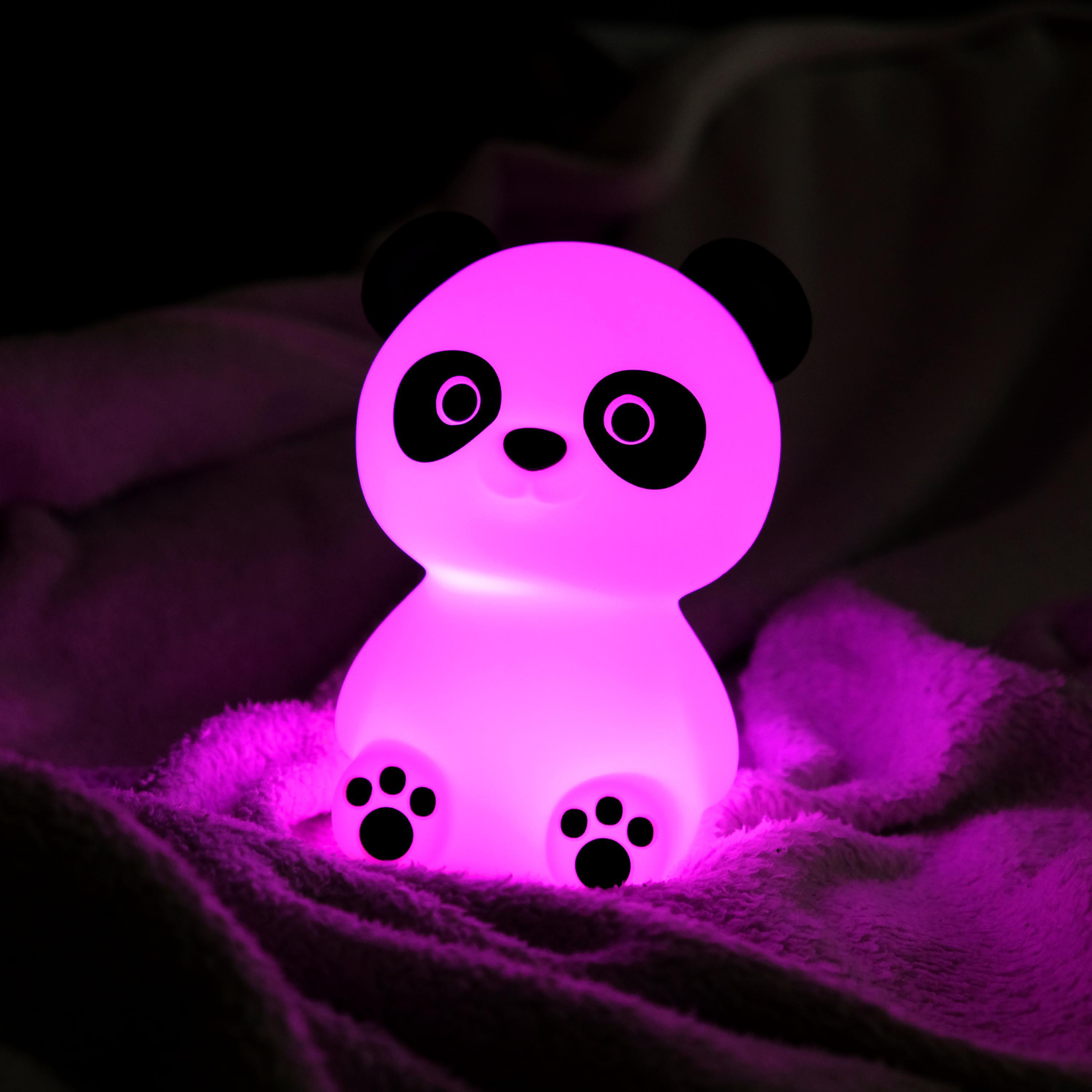 Pinkes Panda-Nachtlicht auf einer Decke, leuchtet sanft.