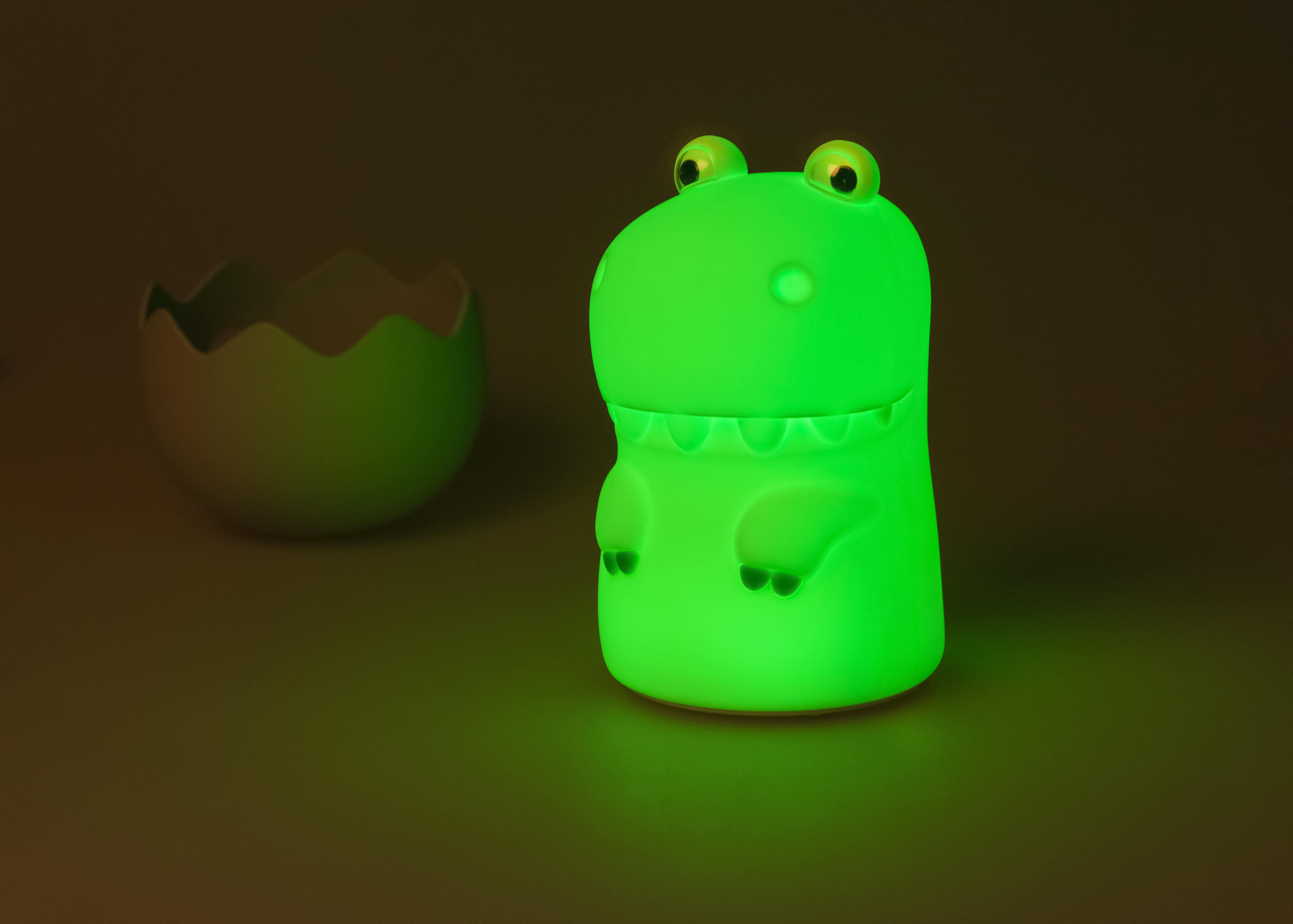 Eine grün leuchtende Dinosaurierlampe neben einer zerbrochenen Eierschale.