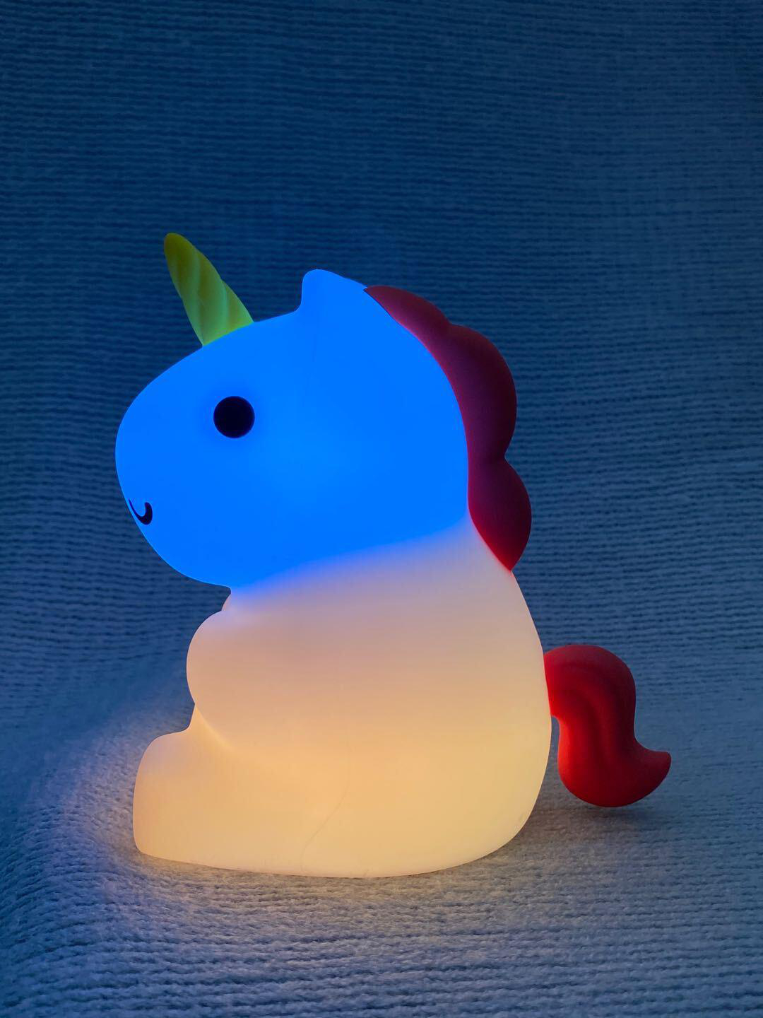 Ein blaues und weißes Einhorn-Nachtlicht auf einer strukturierten Oberfläche.