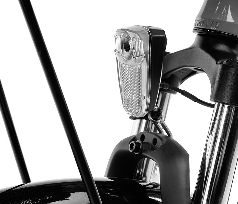 Close-up van de voorlamp van een fiets. Het licht is wit en op de voorvork gemonteerd.