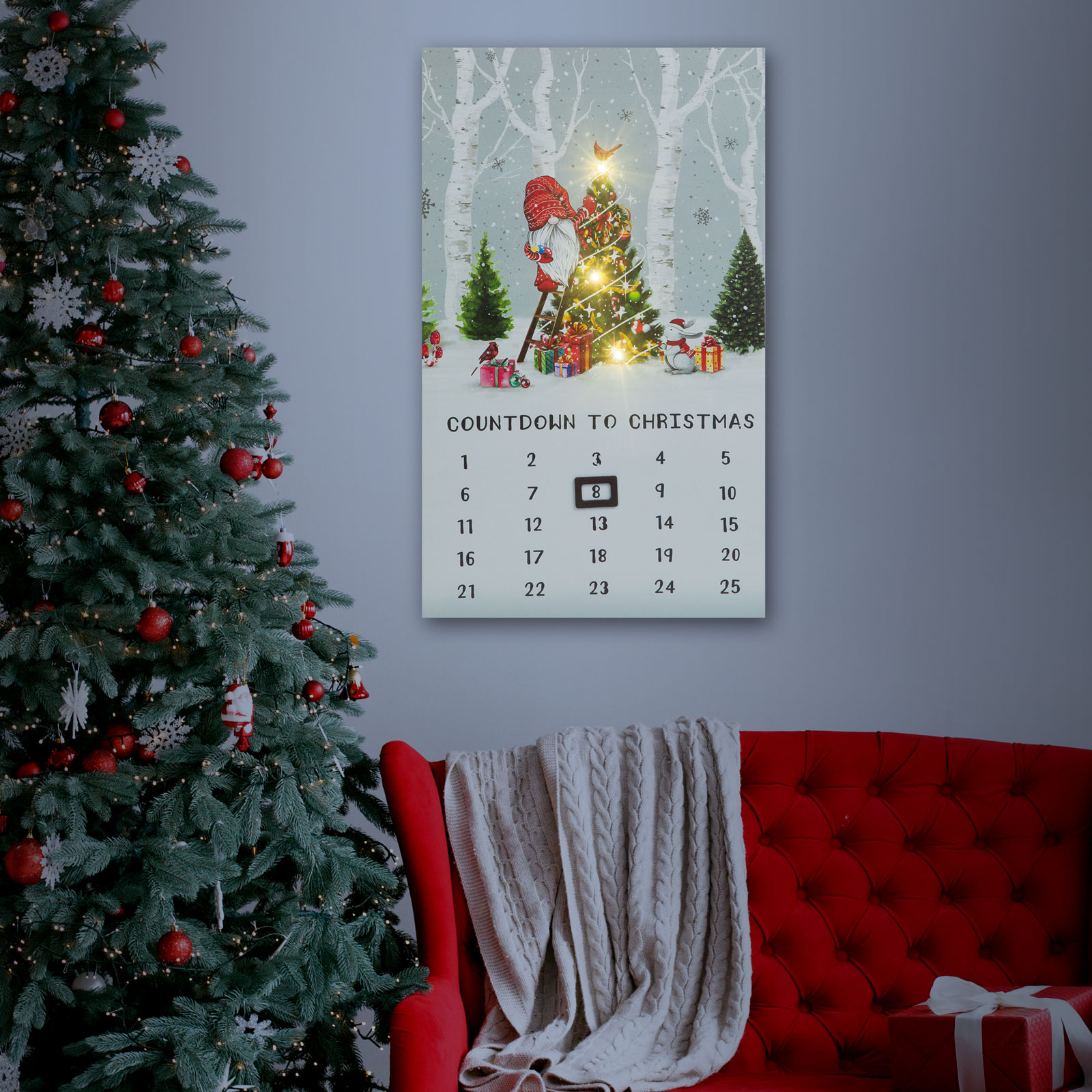 Karácsonyi visszaszámláló naptár a falon, egy díszített fa és egy piros kanapé mellett.