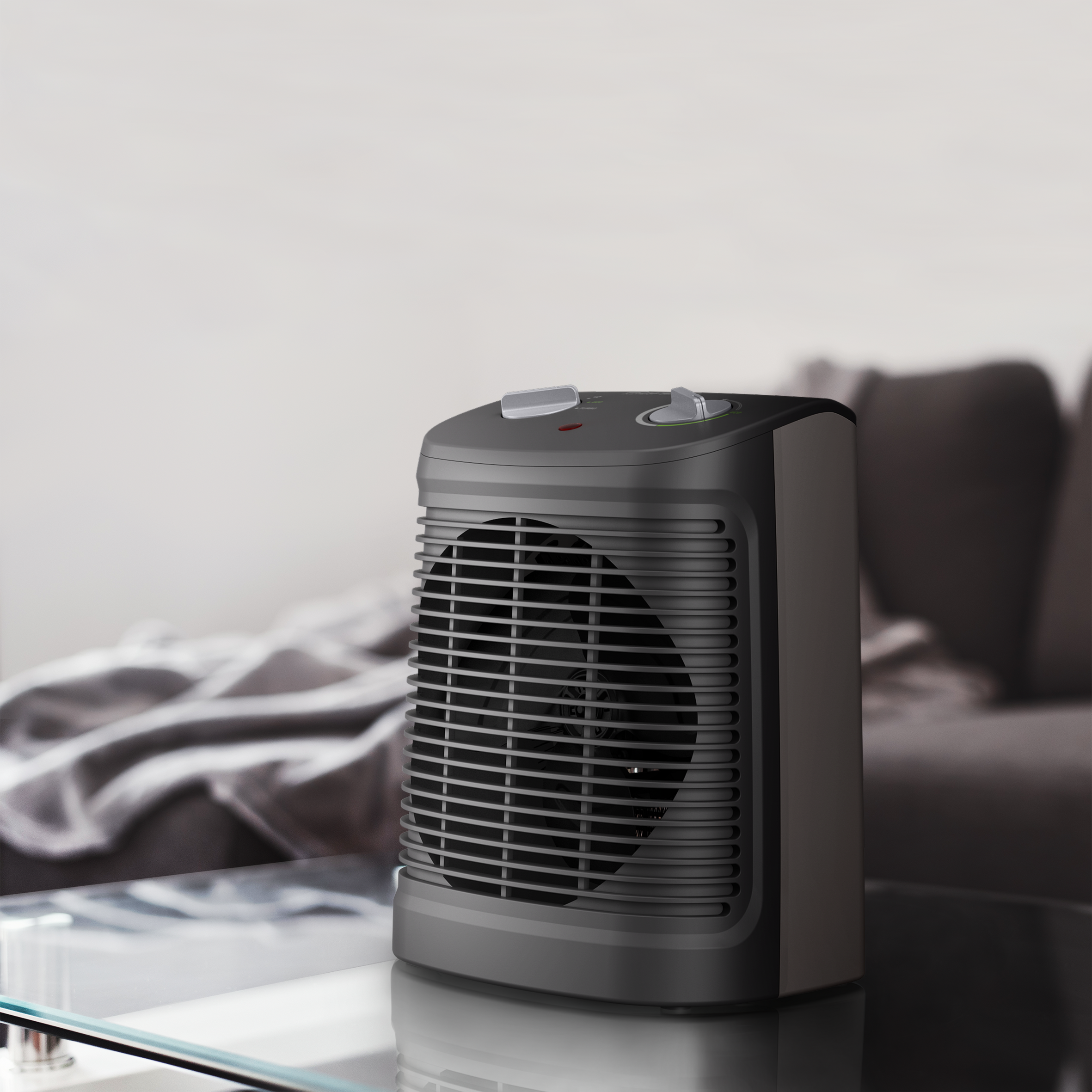 Un calefactor eléctrico negro y gris se encuentra sobre una mesa de vidrio. Un sofá borroso está en el fondo.
